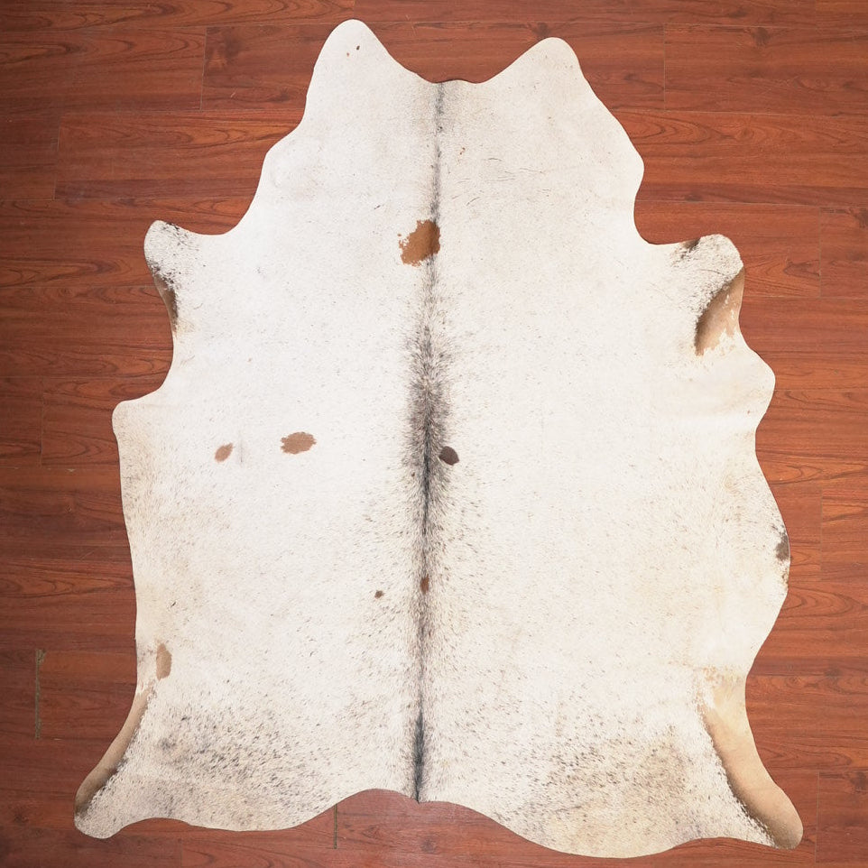 White cowhide rug with horns on a wooden floor