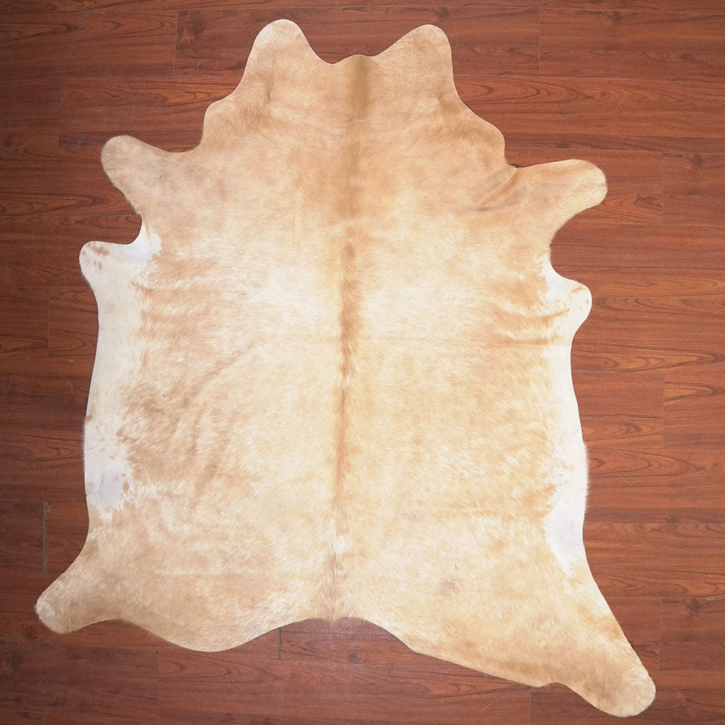 Beige cowhide rug on a wooden floor
