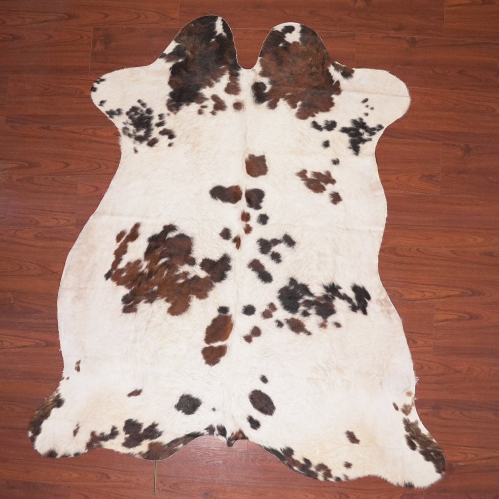 Cowhide rug with brown and black patches on a wooden floor