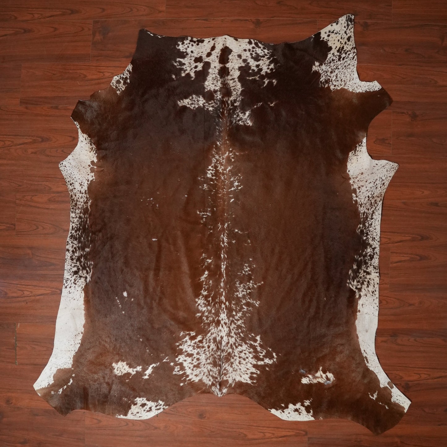 Brown and white cowhide rug on a wooden floor