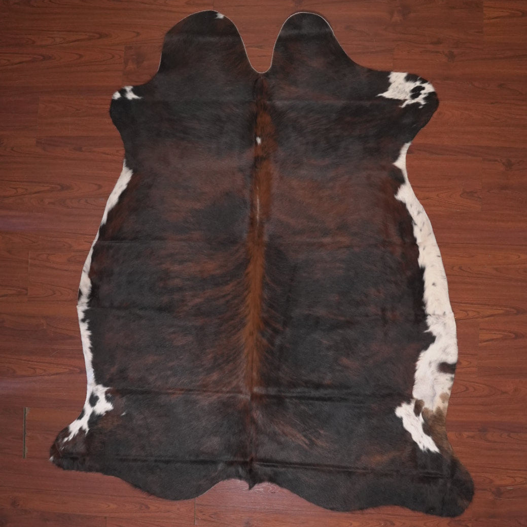 Brown and white cowhide rug on a wooden floor