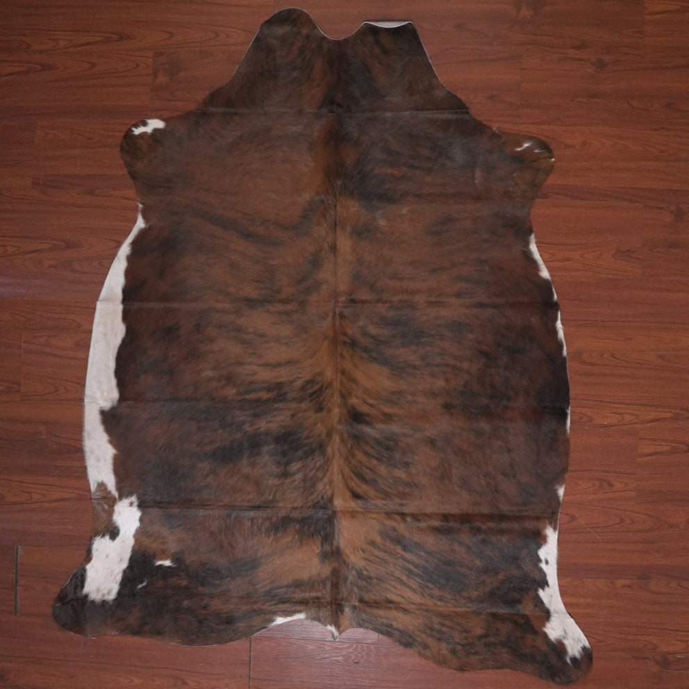 Brown and white cowhide rug on a wooden floor