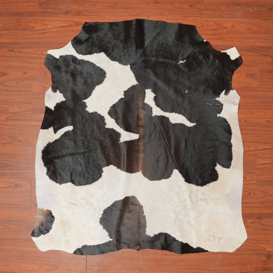 Cowhide rug with black and white pattern on a wooden floor