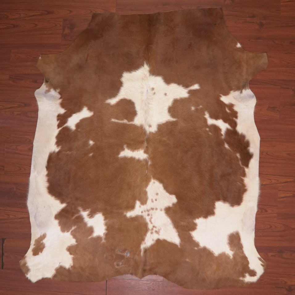 Brown and white cowhide rug on a wooden floor