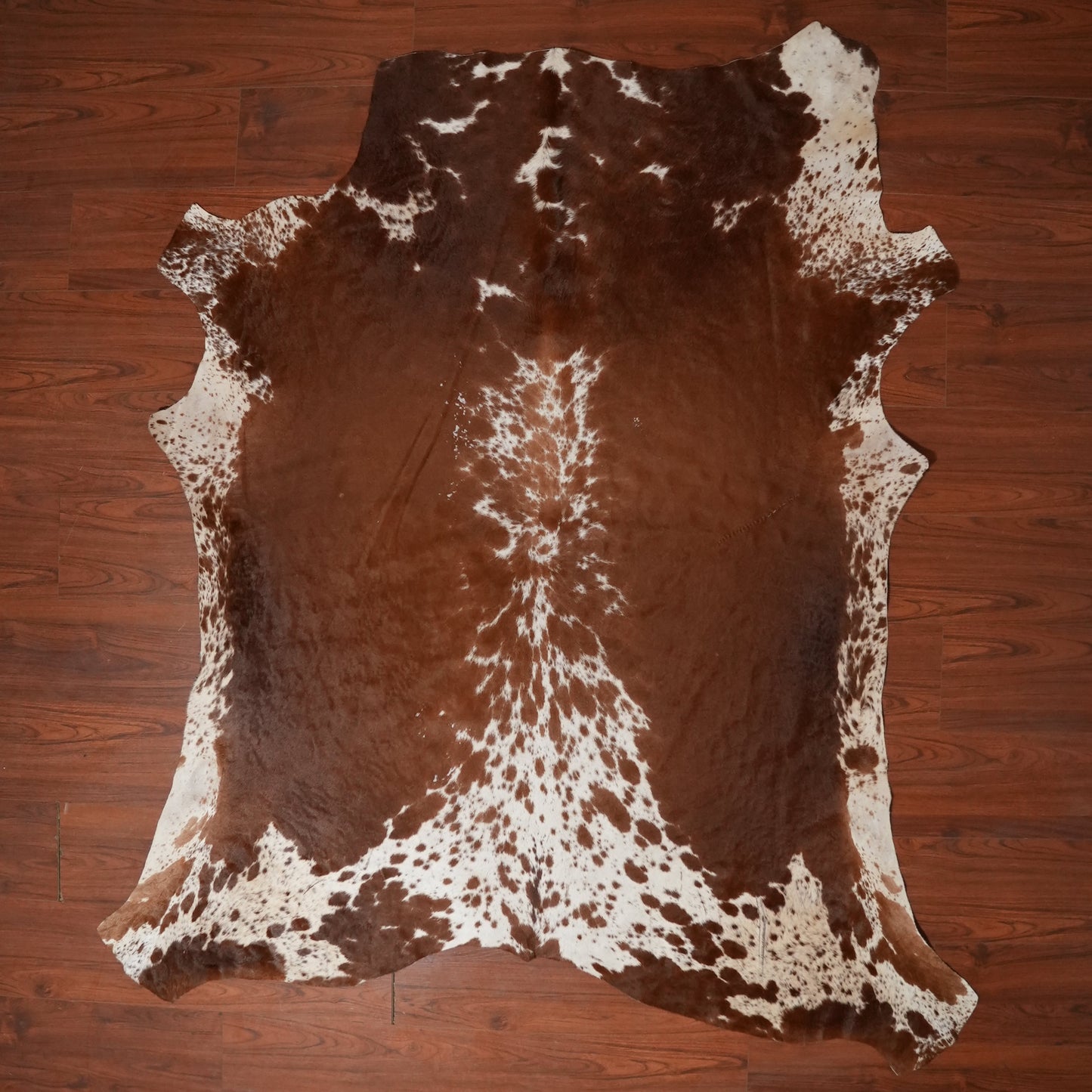 Brown and white cowhide rug on a wooden floor