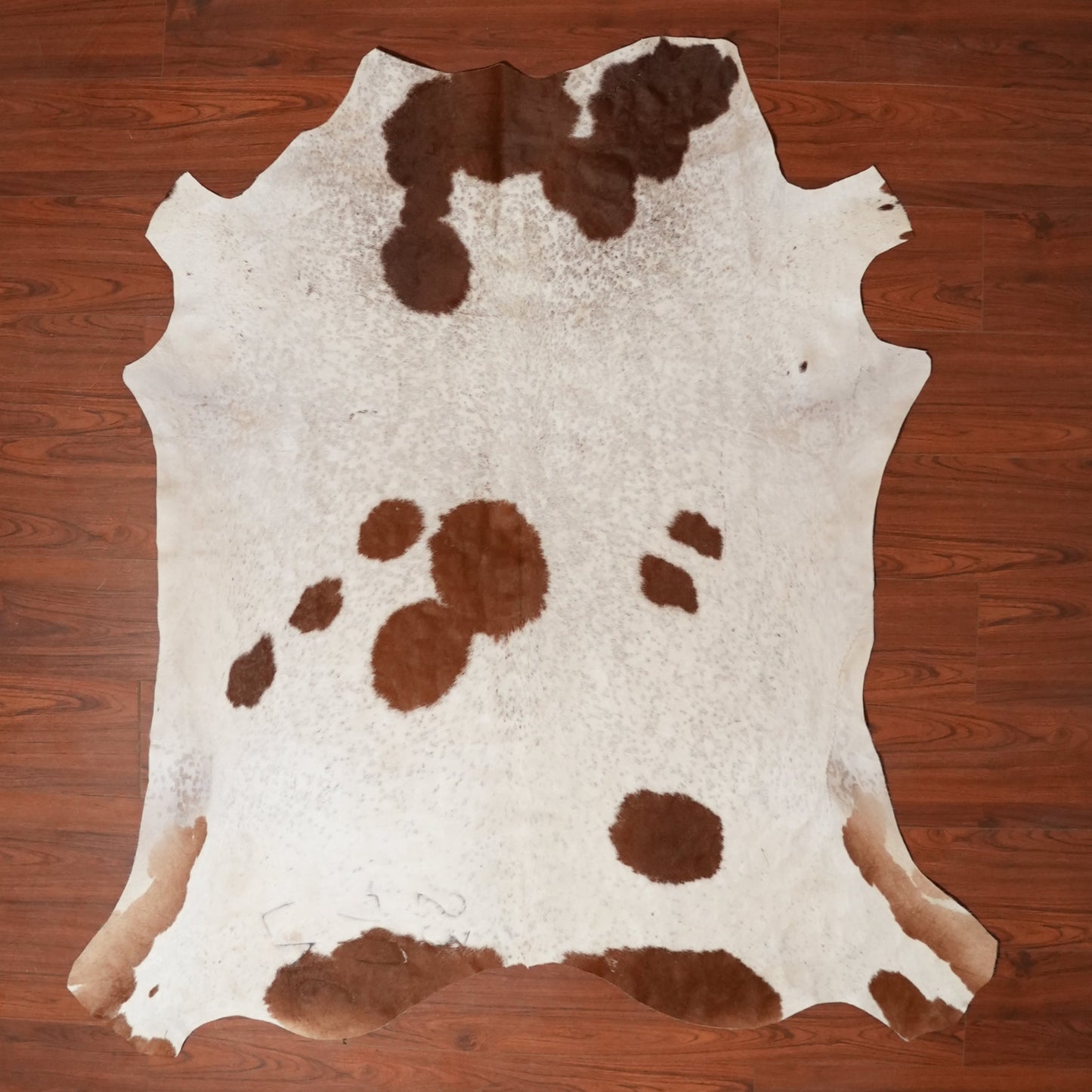 Cowhide rug with brown and white pattern on a wooden floor
