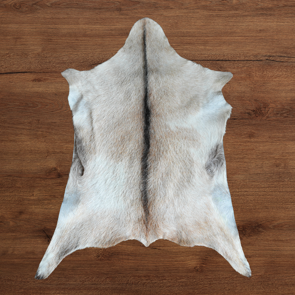 A pale cream and grey goat hide with a central dark stripe, laid flat on a brown wooden surface.