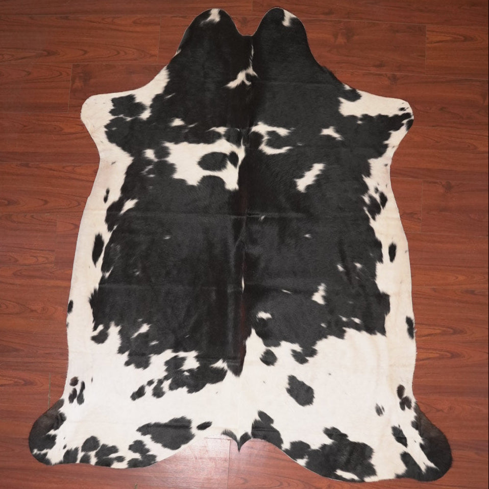 Black and white cowhide rug on a wooden floor