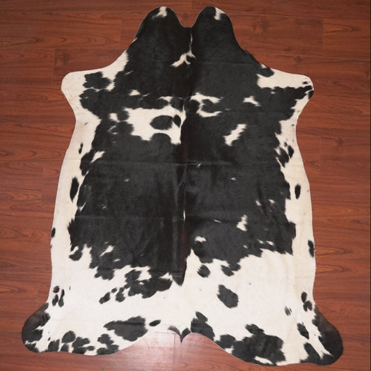Black and white cowhide rug on a wooden floor