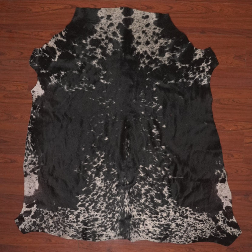 Black and white cowhide rug on a wooden floor