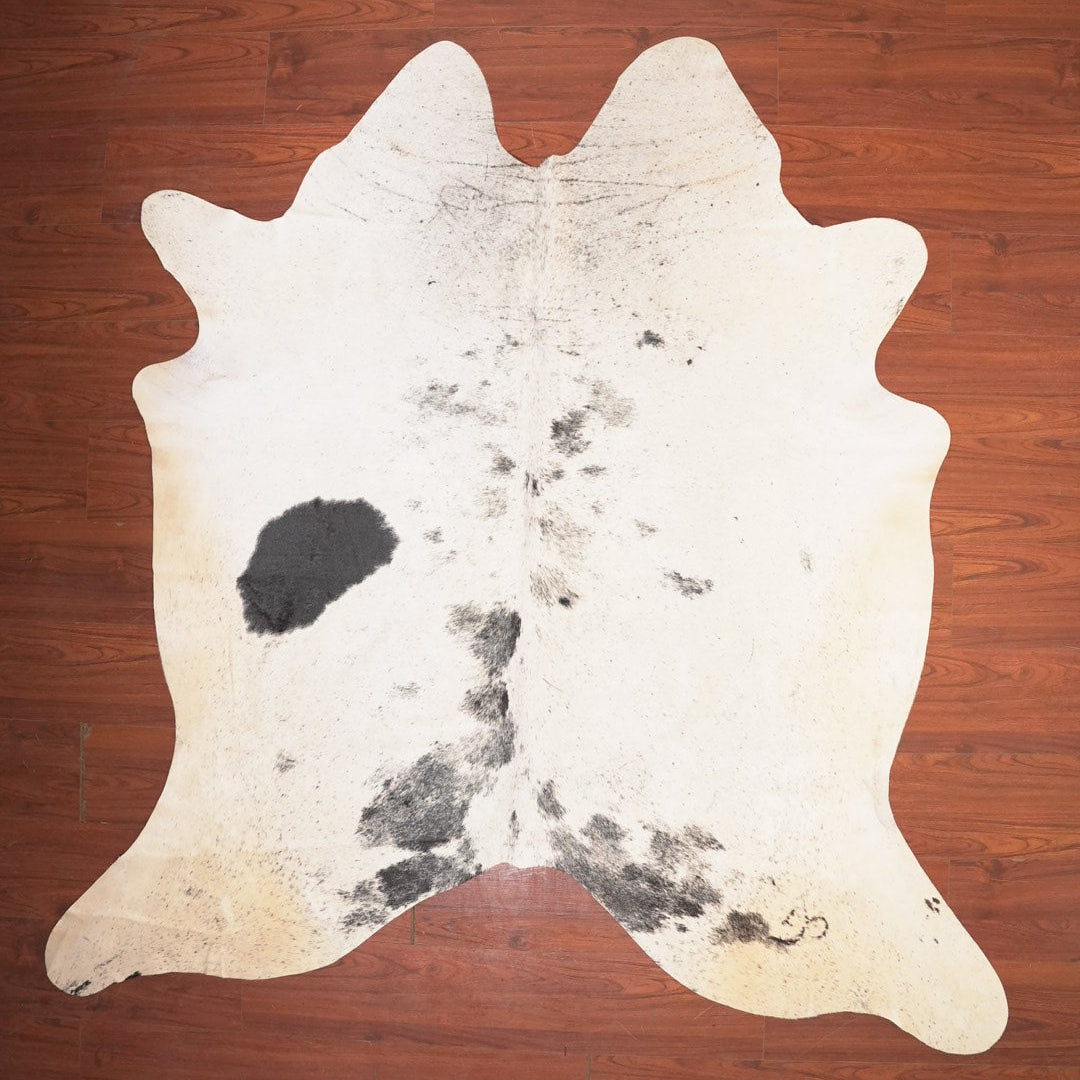 Cowhide rug with black spots on a wooden floor