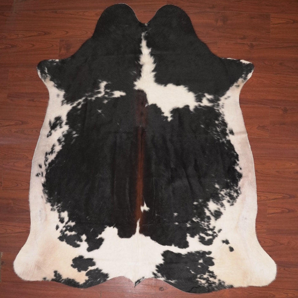 Black and white cowhide rug on a wooden floor