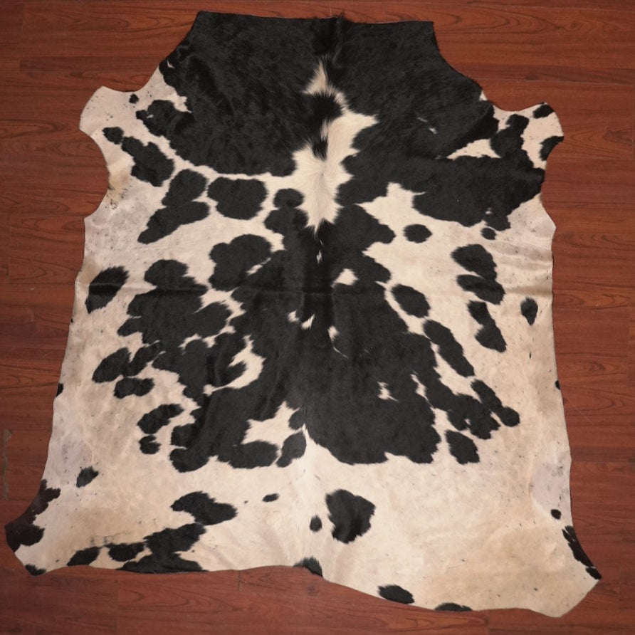 Black and white cowhide rug on a wooden floor