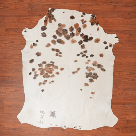 Cowhide rug with brown and black spots on a wooden floor