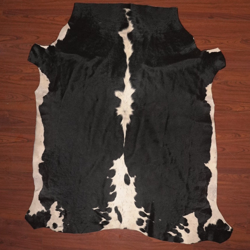 Black and white cowhide rug on a wooden floor