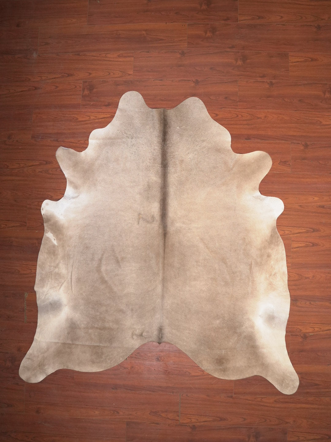 Beige cowhide rug on a wooden floor