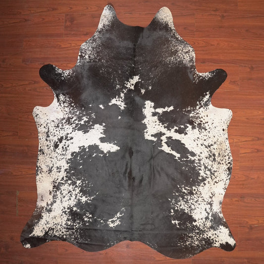 Black and white cowhide rug on a wooden floor