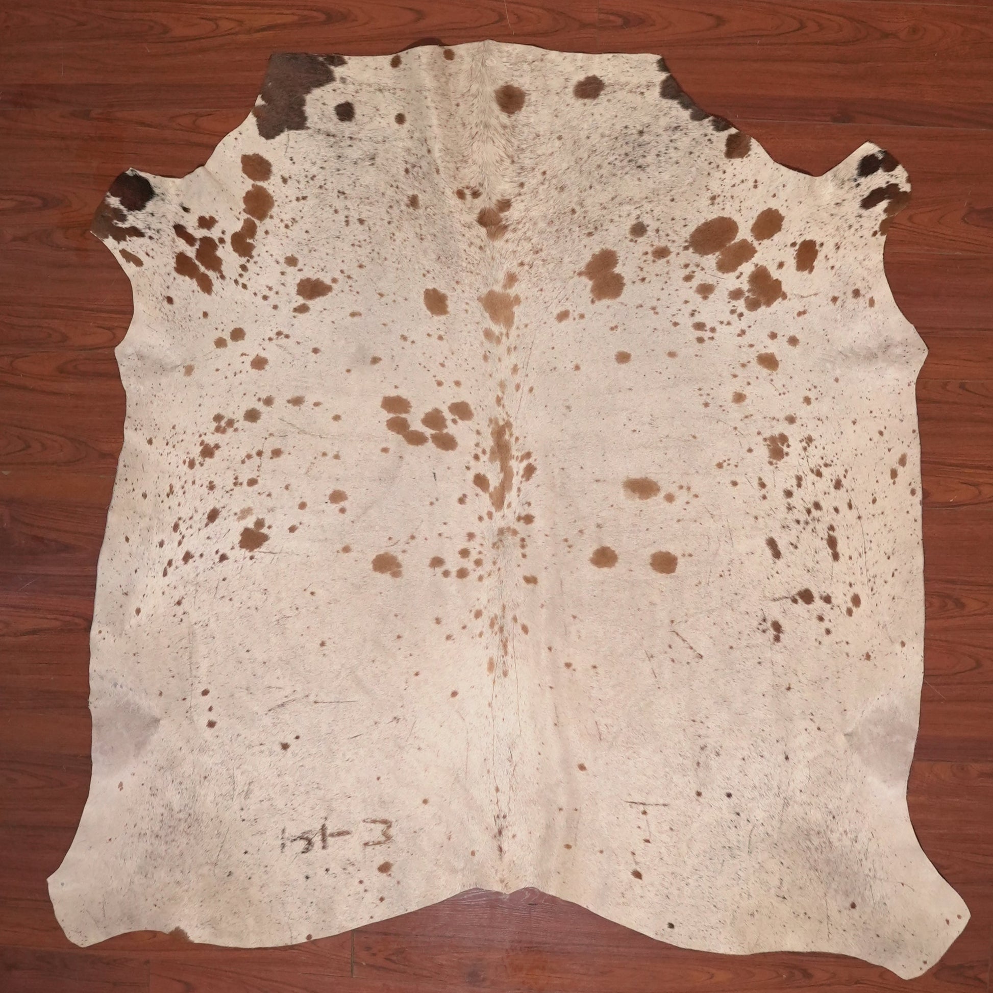 Cowhide rug with brown spots on a wooden floor