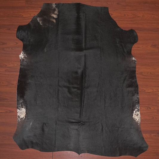 Black cowhide rug on a wooden floor