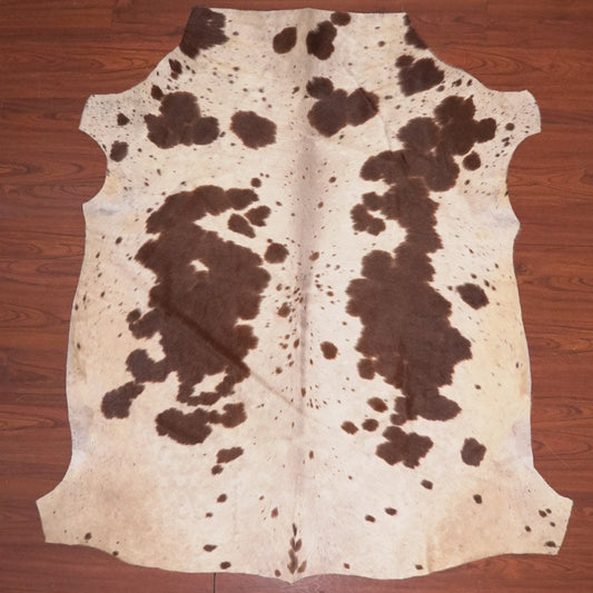 Cowhide rug with brown and white pattern on a wooden floor