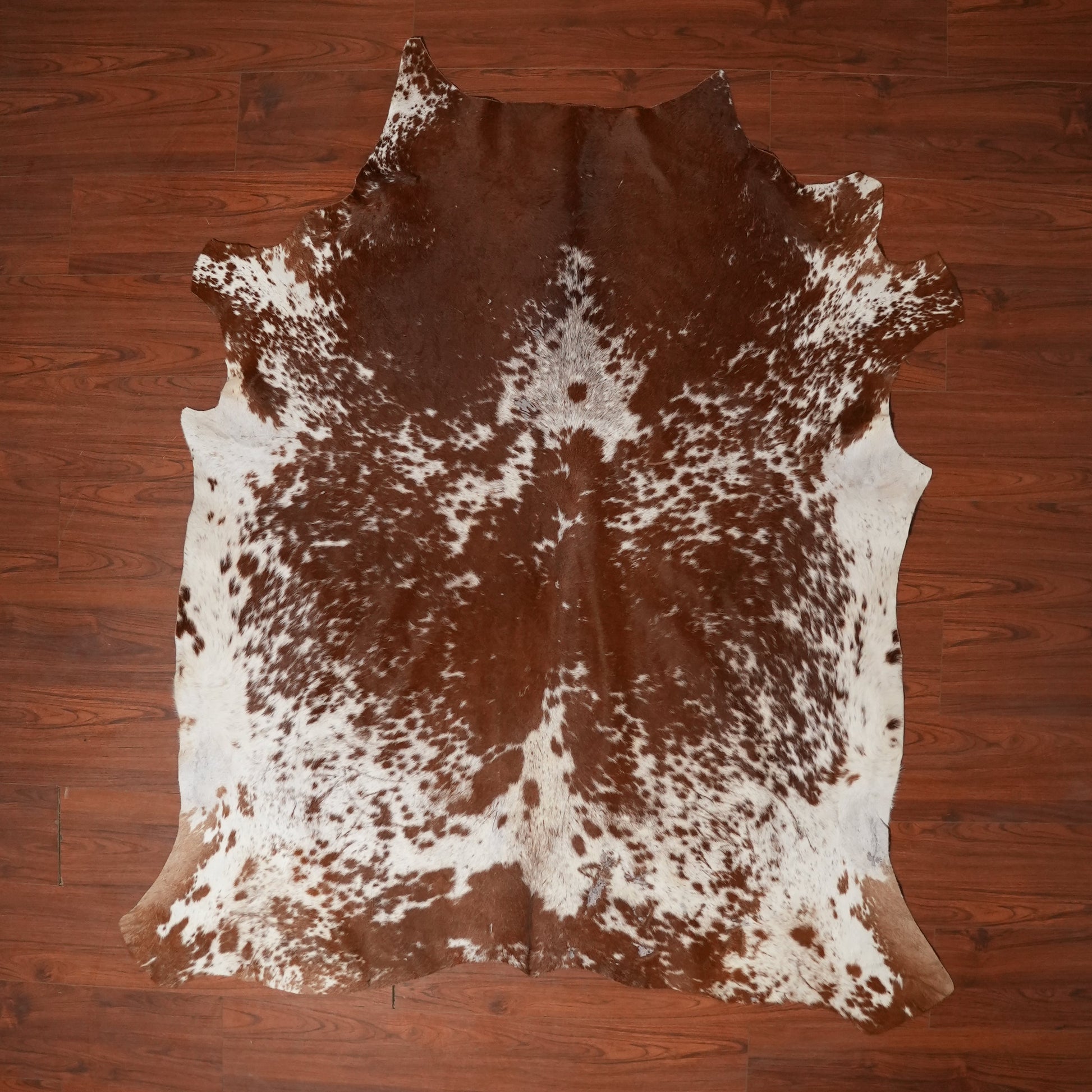 Brown and white cowhide rug on a wooden floor