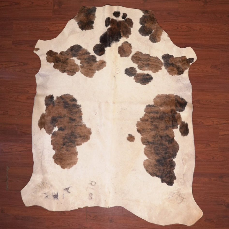 Cowhide rug with brown and black patches on a wooden floor