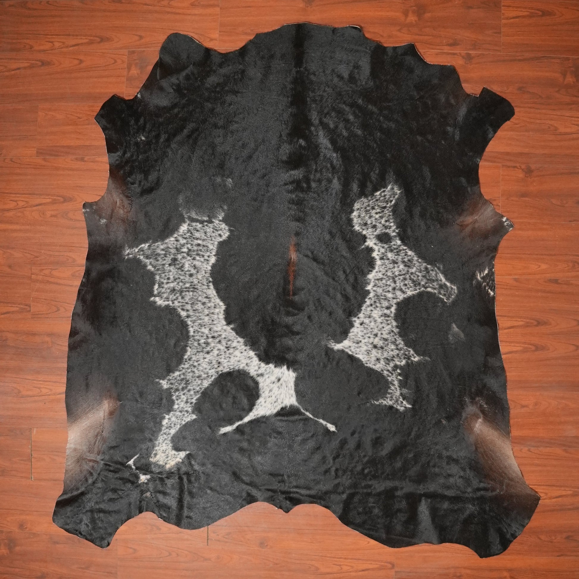 Black and white cowhide rug on a wooden floor