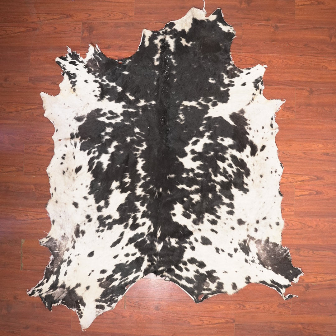 Black and white cowhide rug on a wooden floor