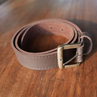 A dark brown leather belt with a metal buckle, coiled on a wooden surface.